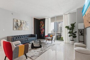 A modern living room with a sofa, armchairs, a coffee table, and a large TV. - Modern Luxury 42nd-Floor Penthouse in Heart of Brickell with 2 private balconies (Miami)
