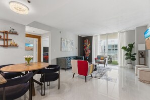 A modern living room with a dining area, a sofa, a colorful chair, and a large window. - Modern Luxury 42nd-Floor Penthouse in Heart of Brickell with 2 private balconies (Miami)