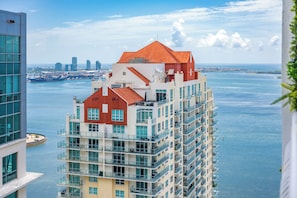 A high-rise hotel with multiple balconies, a red roof, and a view of the water and city skyline. - Modern Luxury 42nd-Floor Penthouse in Heart of Brickell with 2 private balconies (Miami)