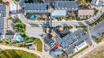 Vista aérea de una zona comercial que incluye un estacionamiento, una piscina y varios edificios.