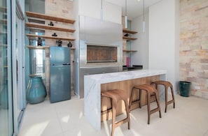 A modern kitchen with a marble countertop, wooden stools, and a built-in oven. - Corporate Stays Habitalis Garay (Asunción)