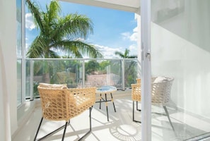 A balcony with wicker chairs and a table, overlooking palm trees and a clear sky. - Corporate Stays Habitalis Garay (Asunción)