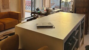 Eine moderne Küche mit einer großen Kochinsel, einem Essbereich mit einer Couch und Blick auf Gebäude durch große Fenster.
