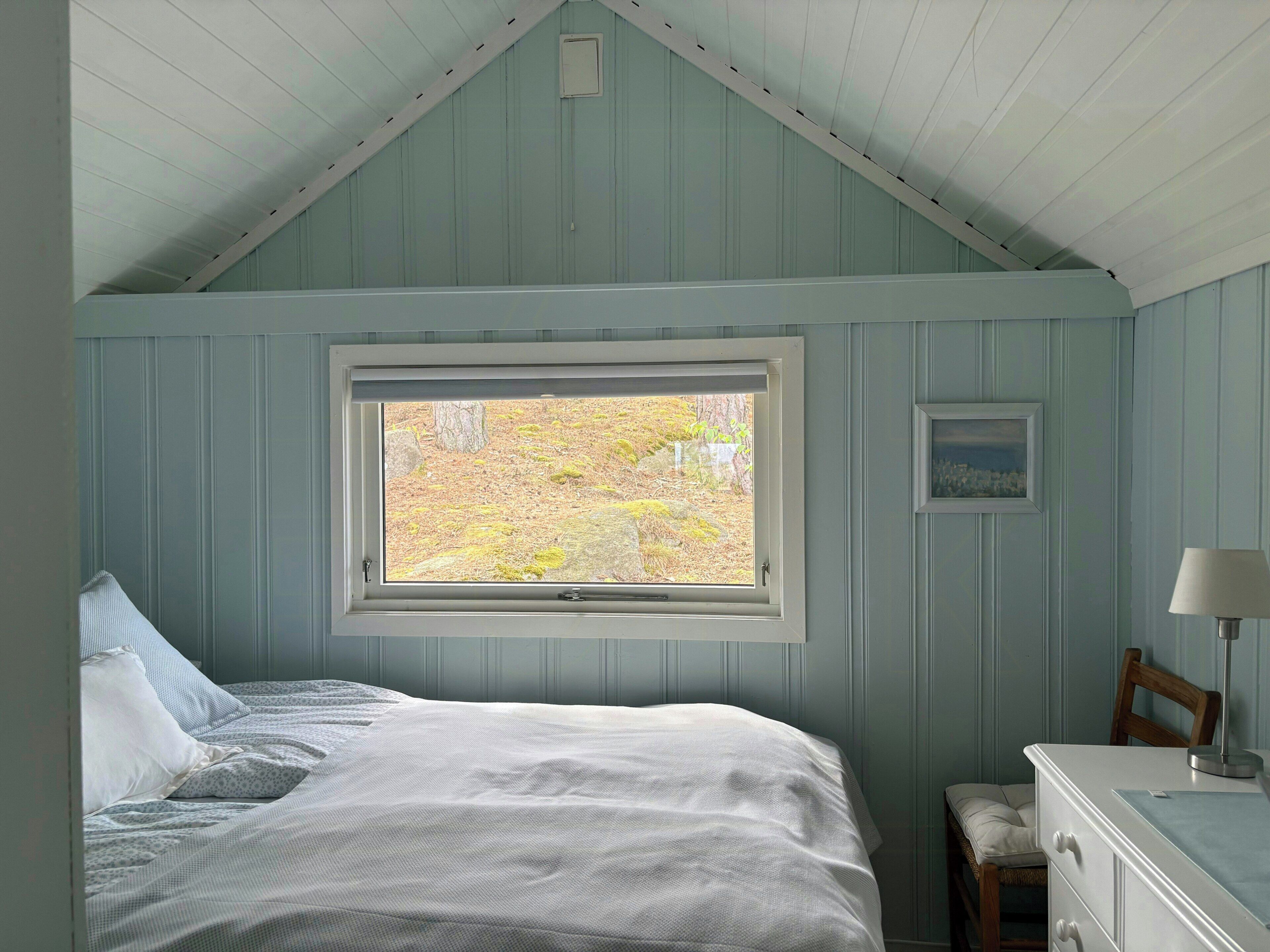 Une chambre à coucher avec un lit, une fenêtre, une commode et une chaise.