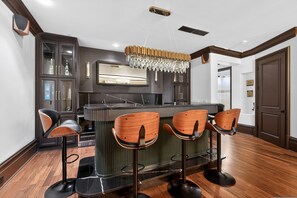 A modern kitchen with dark cabinetry, a central island with bar stools, and a chandelier. - Marietta Mansion in Marietta (Marietta)