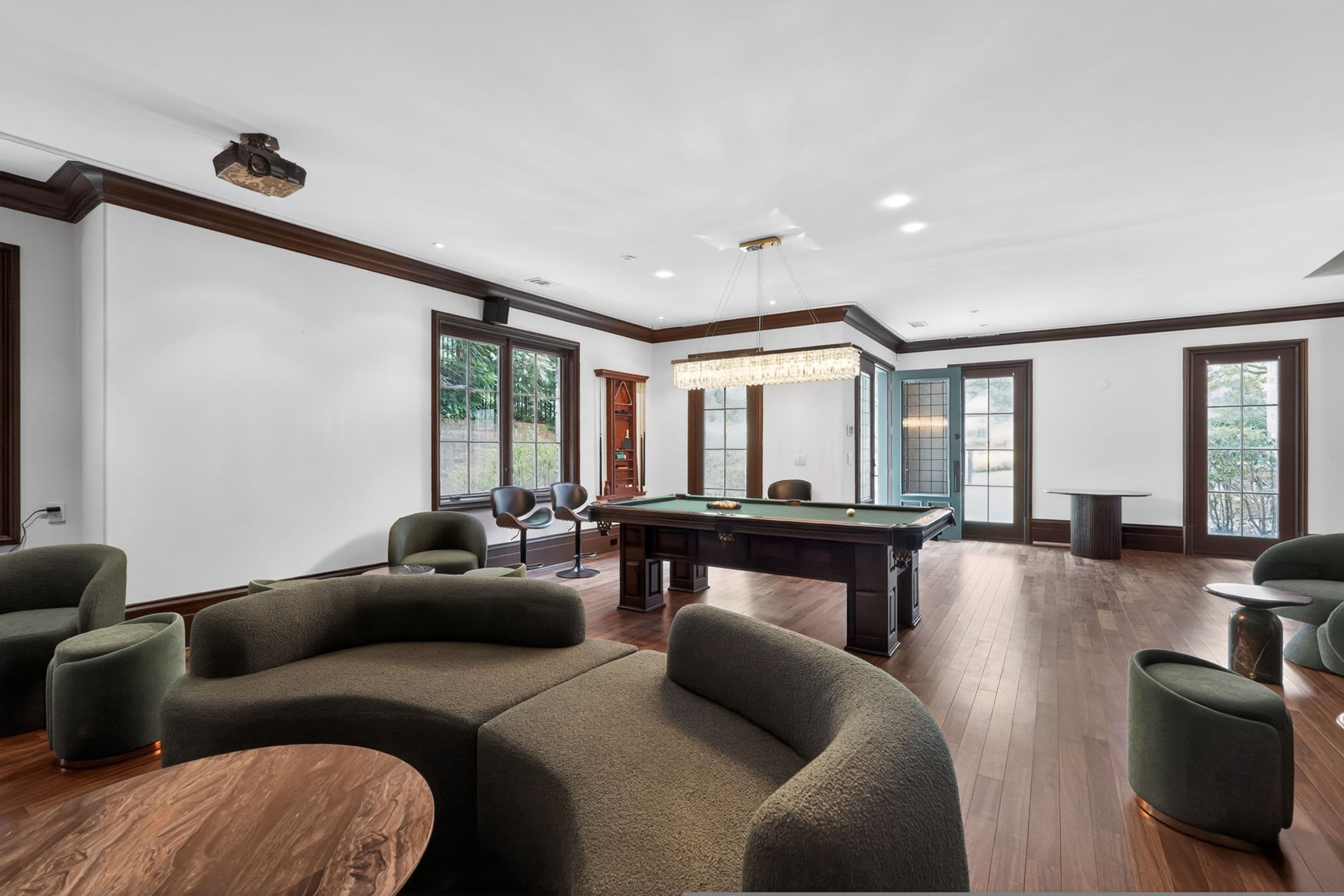 Una habitación amplia con mesa de billar, asientos cómodos y ventanas grandes.