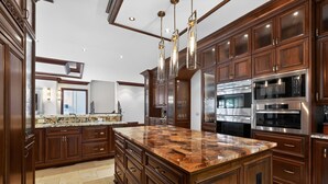 A spacious kitchen with dark wood cabinets, a granite countertop, stainless steel appliances, and pendant lighting. - Marietta Mansion in Marietta (Marietta)