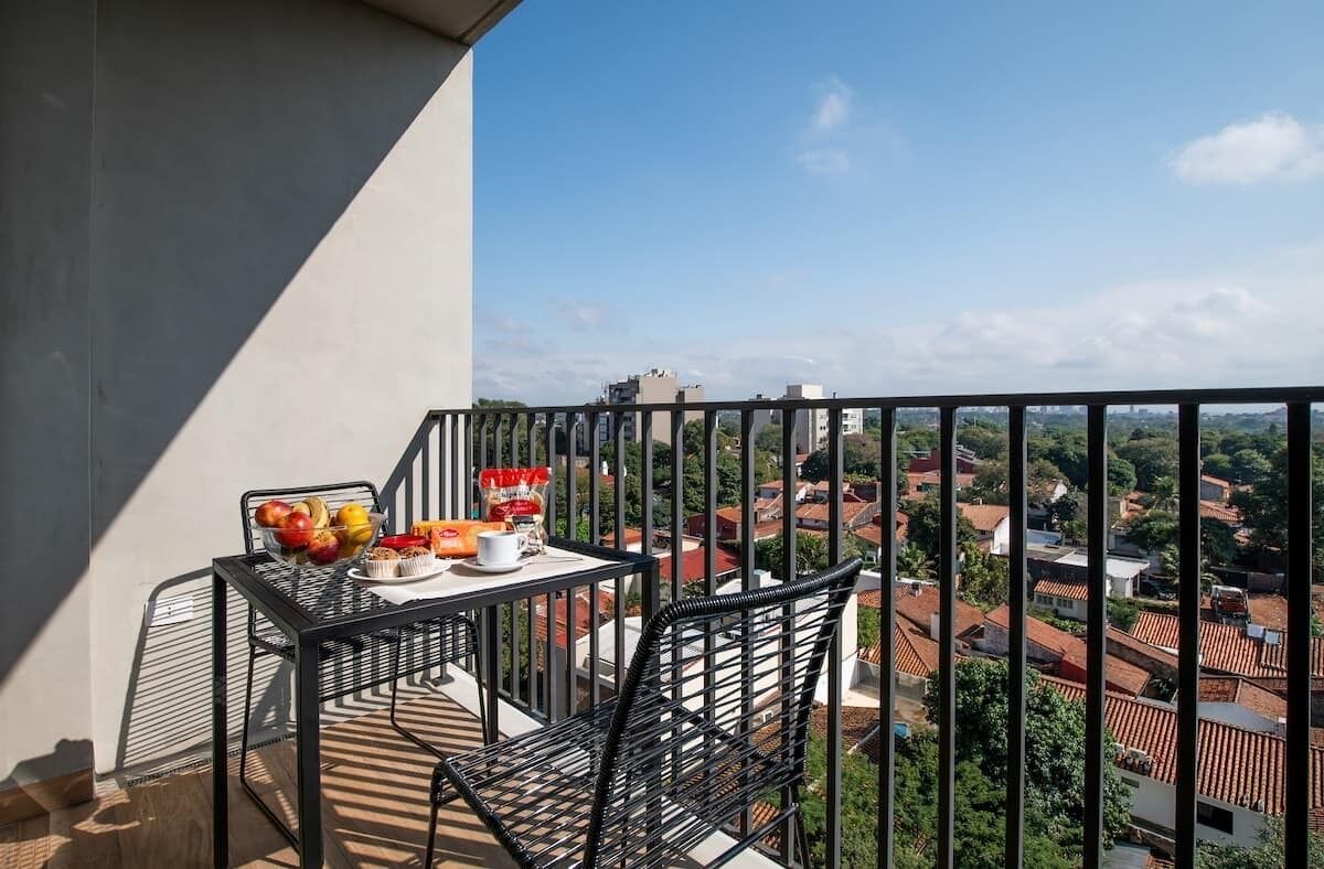 Ein Balkon mit Tisch und Stühlen, einer Obstschale und einer Tüte Snacks.