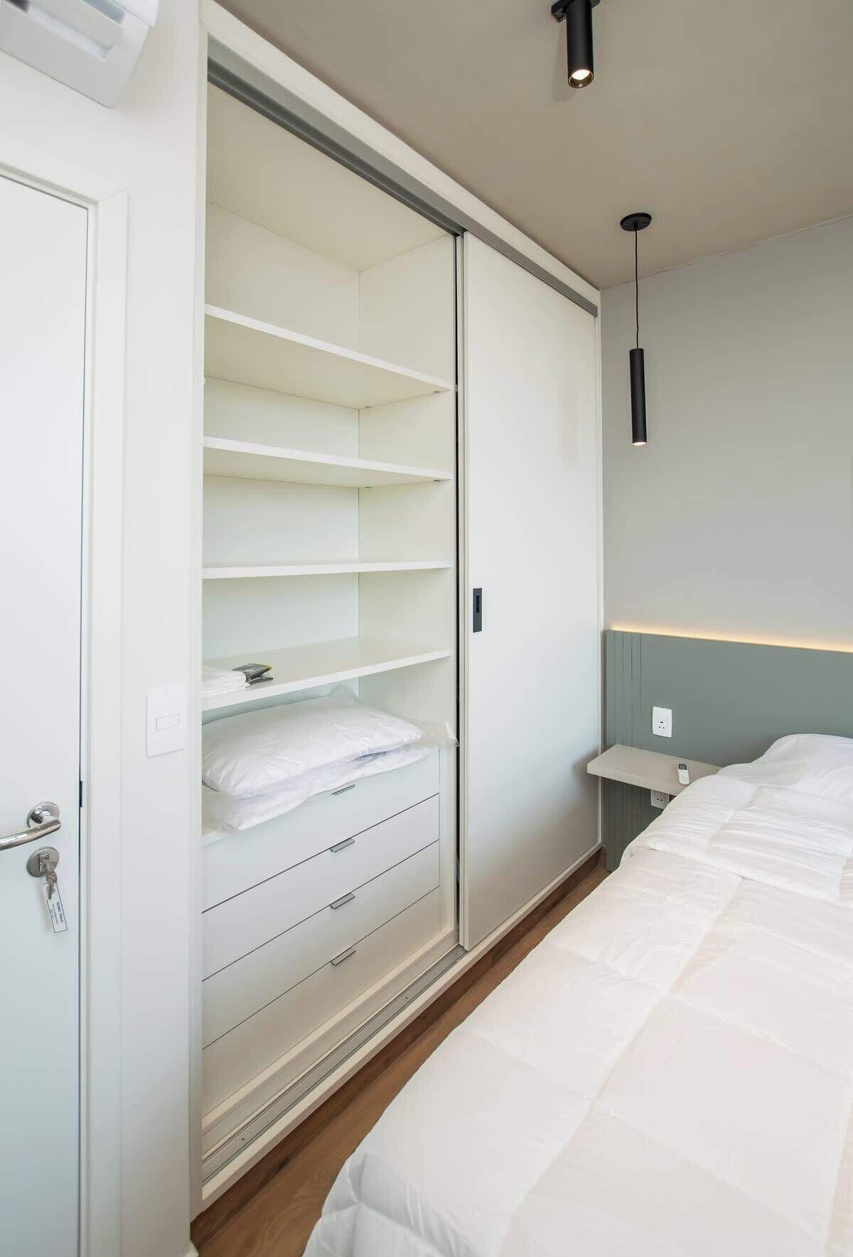 Ein Schlafzimmer mit einem Bett, einem Schrank mit Schiebetüren, einem Nachttisch und einer Hängeleuchte.