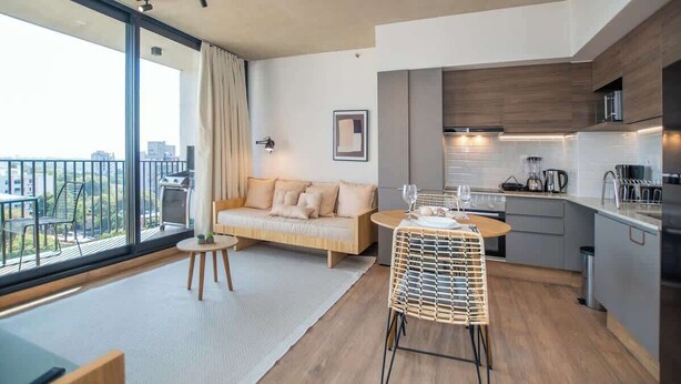 Un appartamento moderno con un balcone, angolo cottura, divano e zona pranzo.