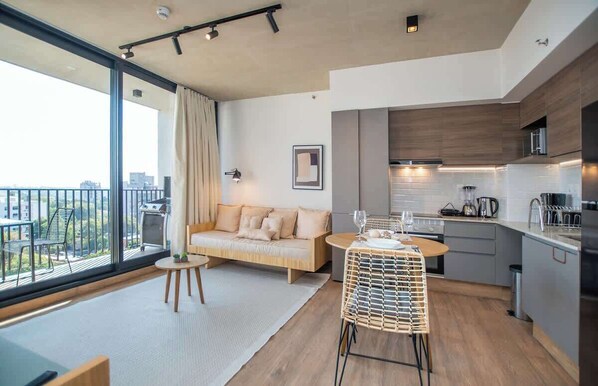 Un apartamento moderno con balcón, kitchenette, sofá y comedor.