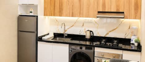 A compact kitchen with a washing machine, a refrigerator, a sink, and a dining area with a table and chairs.