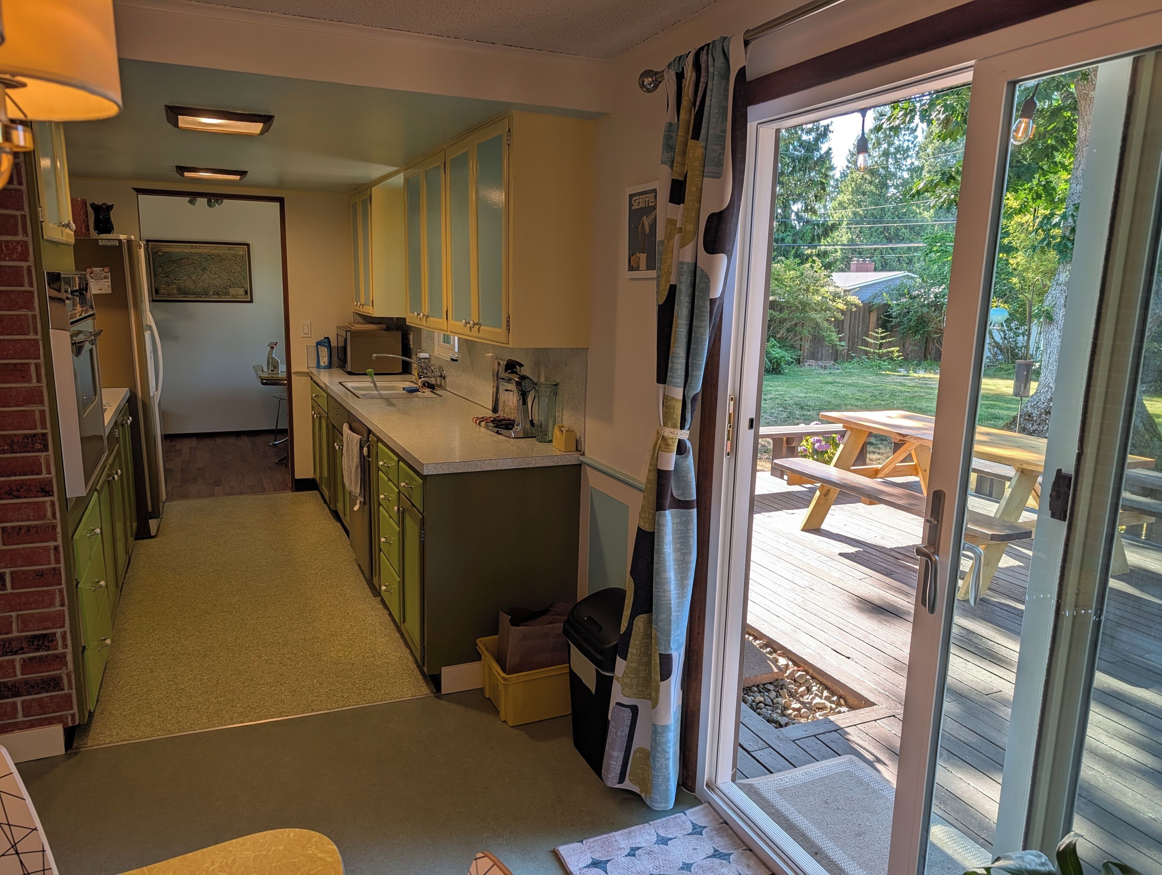 A kitchen with a dining area, a patio with a table and chairs, and a view of a backyard.