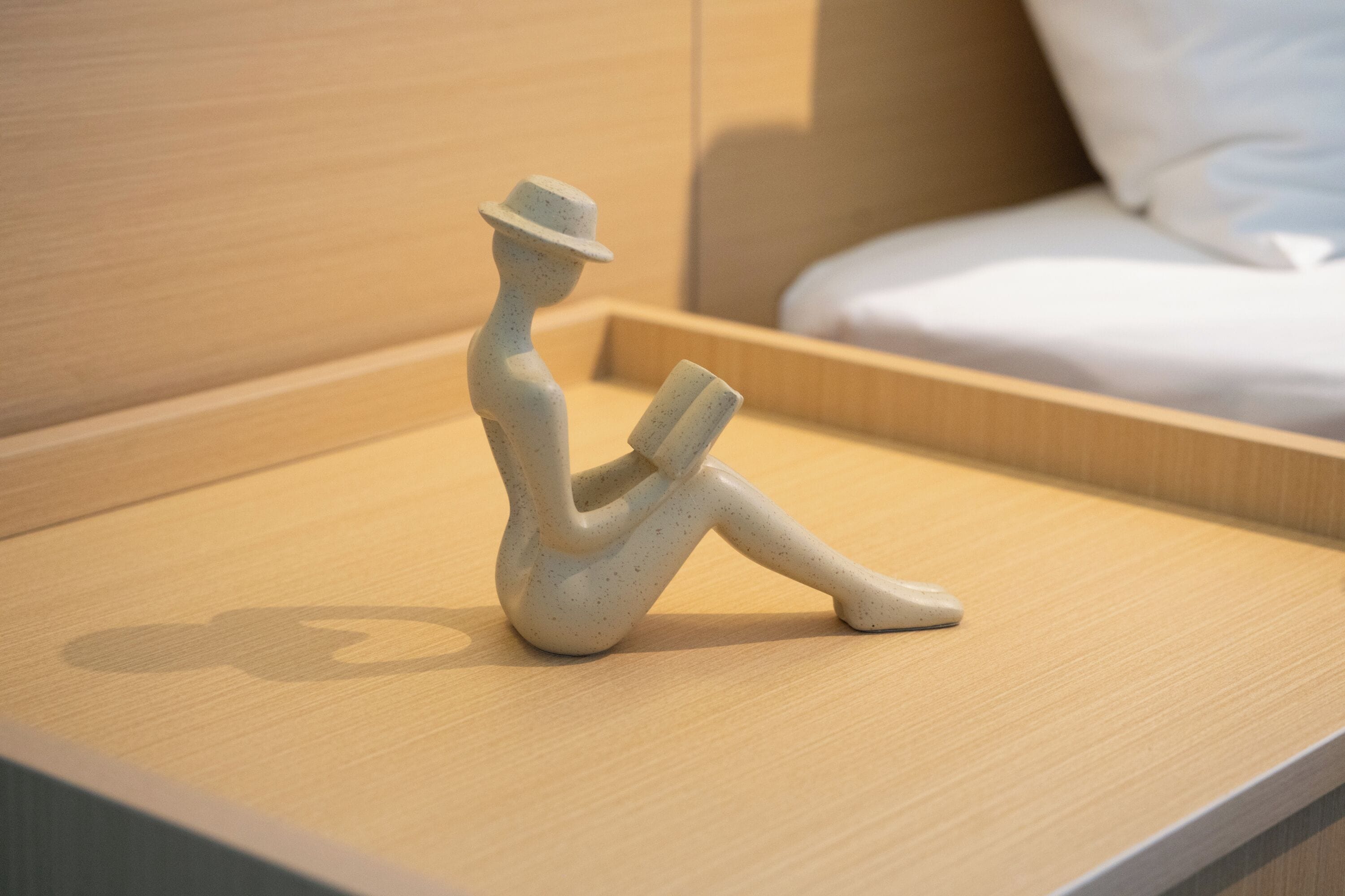 Une sculpture minimaliste représentant une figure assise, posée sur une surface en bois.