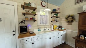 A kitchen with white cabinets, a wooden countertop, a sink, and various kitchen items.