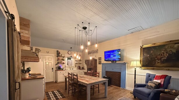A cozy living room with a fireplace, a television, and a dining area with wooden furniture.