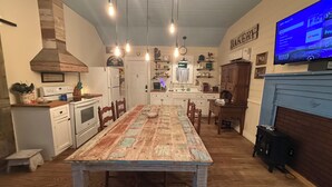 A kitchen with a dining table, wooden cabinets, a stove, and a TV mounted on the wall.