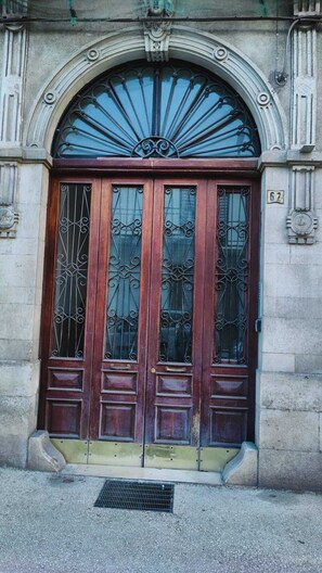 A double wooden door with glass panels and a metal sunburst design above it.