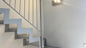Portaat, joissa on kiviseinä, metallikaide ja seinään kiinnitetty valaisin.