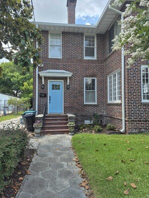 A two-story brick house with a blue front door, a small porch, and a clear sky. - Le Magnolia Magnifique: a 3-bedroom townhome in historic Riverside (Jacksonville)