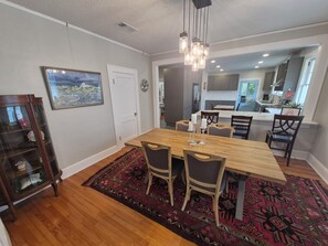 A dining area with a wooden table, chairs, and a patterned rug. - Le Magnolia Magnifique: a 3-bedroom townhome in historic Riverside (Jacksonville)