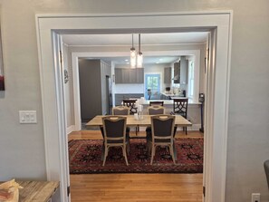 A dining area with a table and chairs, a rug, and a kitchen in the background. - Le Magnolia Magnifique: a 3-bedroom townhome in historic Riverside (Jacksonville)