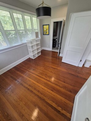 A room with hardwood flooring, a white basket, a black pendant light, and a door leading to another room. - Le Magnolia Magnifique: a 3-bedroom townhome in historic Riverside (Jacksonville)