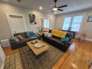 A living room with a sofa, coffee table, and a ceiling fan. - Le Magnolia Magnifique: a 3-bedroom townhome in historic Riverside (Jacksonville)