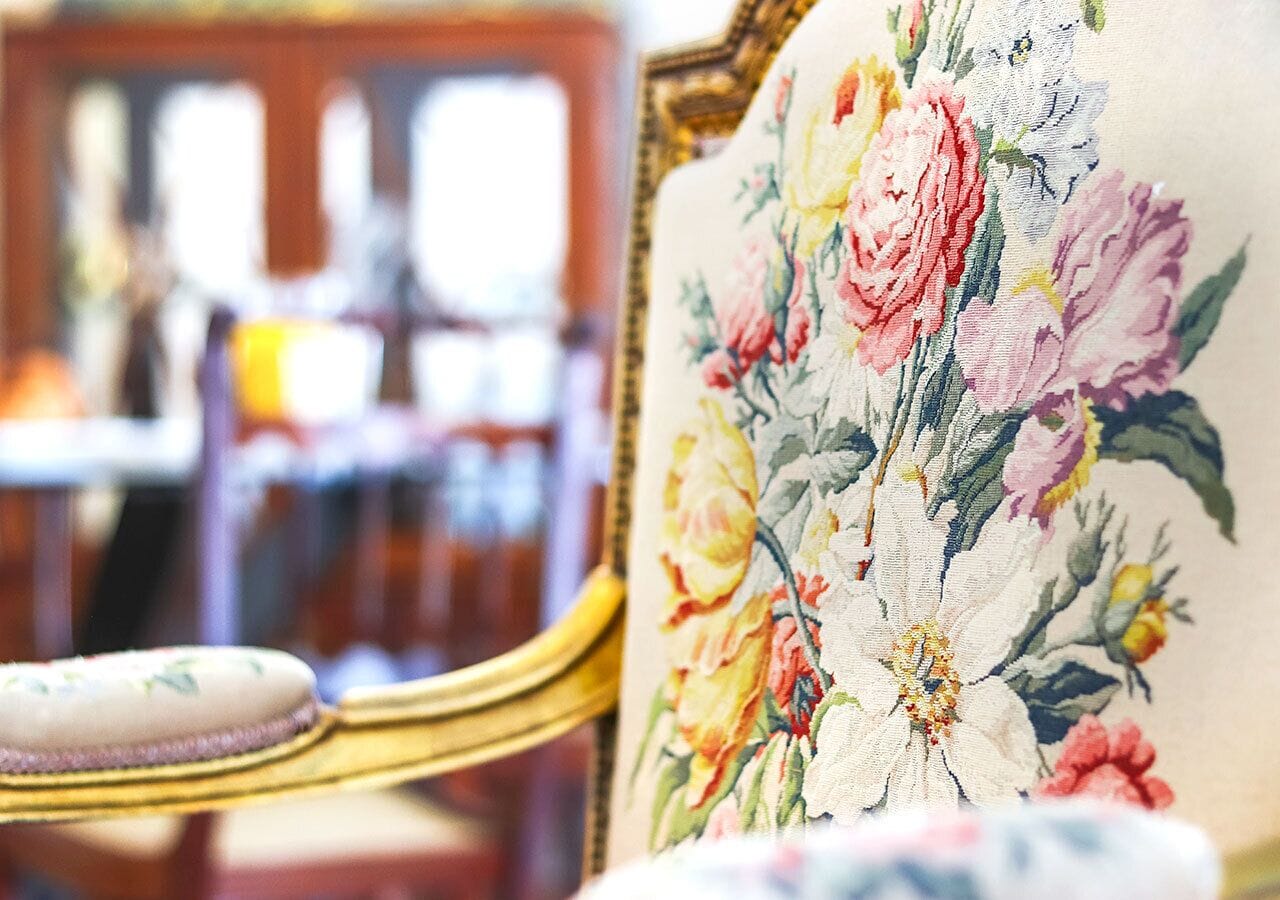 A close-up of a chair with a floral upholstery pattern.