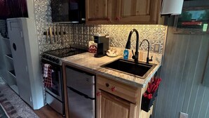 A kitchen with wooden cabinets, a stainless steel refrigerator, a microwave, and a sink.