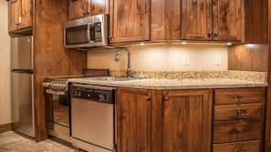 Una cocina con armarios de madera, electrodomésticos de acero inoxidable, encimera de granito y lavavajillas.