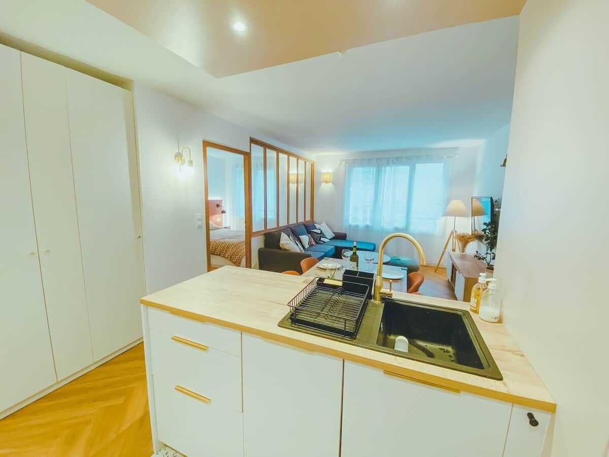 Une cuisine compacte avec un évier, un coin repas comprenant une table et des chaises, et une chambre avec un lit et une fenêtre.