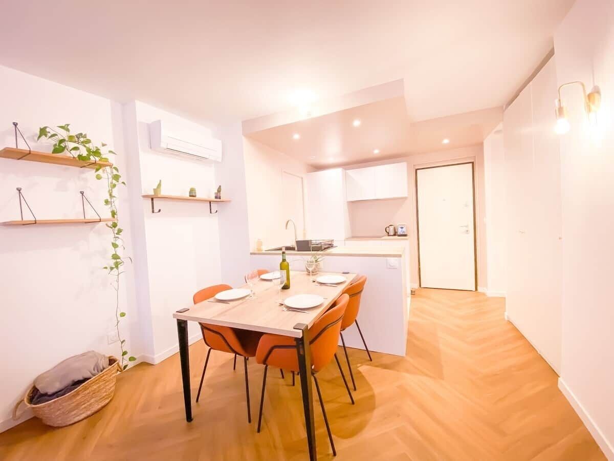 Une cuisine compacte avec un coin repas, un plancher en bois et une petite plante accrochée au mur.