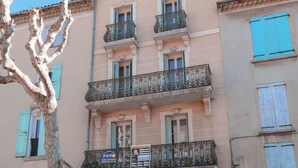 Un edificio de varios pisos con balcones, una puerta y un cartel.