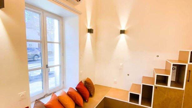 Un interior moderno con un banco incorporado, una escalera y un ventanal con vista a la calle.