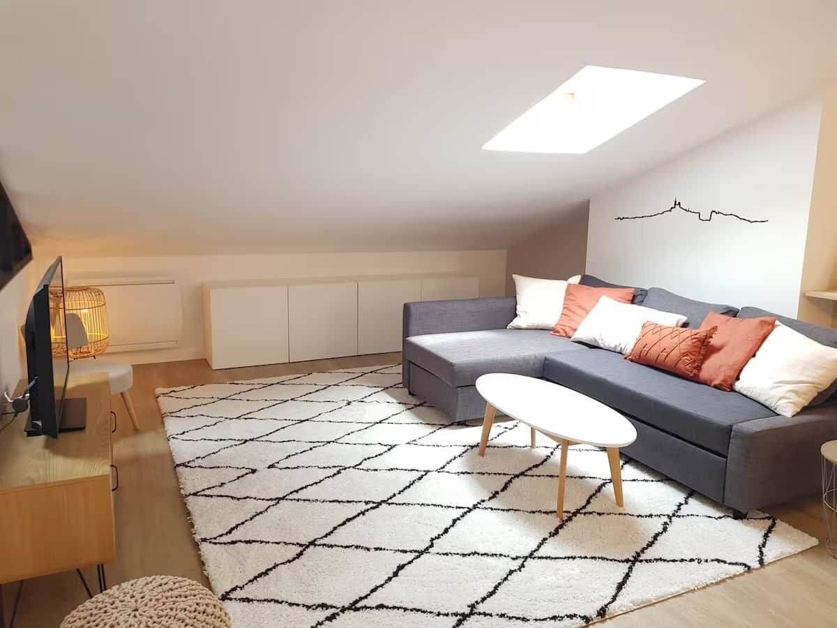 A modern living room with a sofa, coffee table, and a TV on a stand.