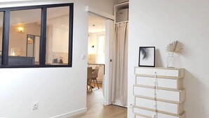 Een modern interieur met een groot raam, een witte ladenkast en een zichtbare badkamer.
