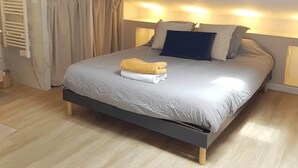Een slaapkamer met een bed, dakraam, verwarming en gordijn.