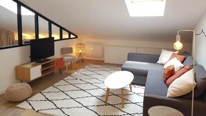 Een moderne woonkamer met een flatscreen televisie, een bank, een salontafel en een kamerbreed tapijt met een patroon.
