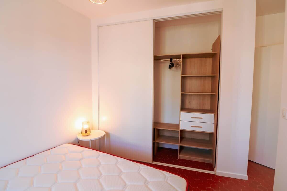Une chambre à coucher avec un lit, une armoire et une table de chevet avec une lampe.