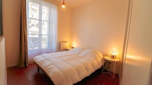 Ett sovrum med en säng, ett fönster och två sänglampor.