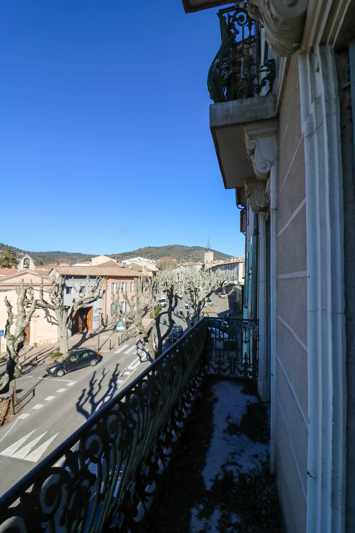 Ein Balkon mit Blick auf eine Straße und Gebäude, inklusive Geländer und blauem Himmel.