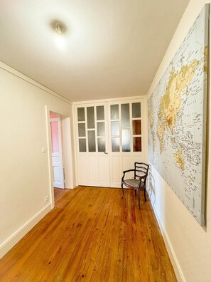 A room with wooden flooring, a white door with frosted glass panels, and a large world map on the wall. - Cozy Cottage at the Forest Edge (Xonrupt-Longemer)