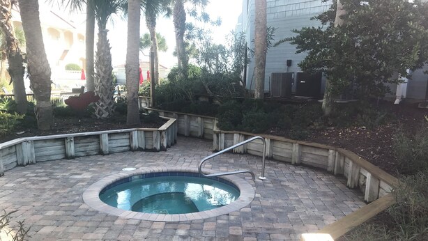 A swimming pool with a wooden deck, surrounded by a brick patio and wooden railings. - Beautiful 2-bedroom oceanfront condo sleeps up to 7 in St. Augustine Beach (St. Augustine)