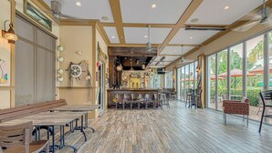 Un amplio espacio interior con piso de madera, una barra y diferentes disposiciones de asientos.
