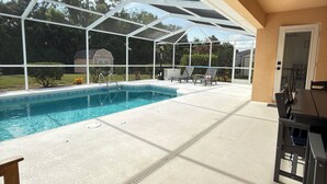 A covered outdoor swimming pool with a patio area, including a table and chairs. - Quaint, modern 3-bedroom house in charming, historic Inverness Florida. (Inverness)