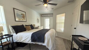 A bedroom with a bed, a ceiling fan, a desk, a chair, a rug, and a door. - Quaint, modern 3-bedroom house in charming, historic Inverness Florida. (Inverness)
