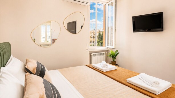Ein Hotelzimmer mit einem Bett, zwei Spiegeln, einem Fernseher, einem Fenster mit Blick und einer Heizung.