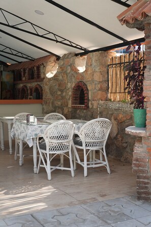 An outdoor patio with stone walls, a brick archway, and white wicker furniture.