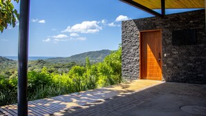 A modern building with a stone facade, a wooden door, and a view of a mountainous landscape. - Ocean view · infinity pool · fully equipped private spa (Playa Grande)